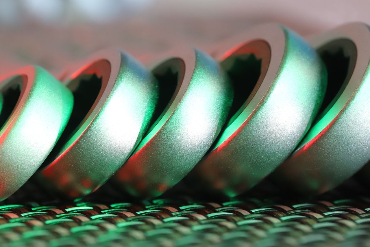 Macro shot of metallic spiral with vibrant green and red light reflections, highlighting texture and form.