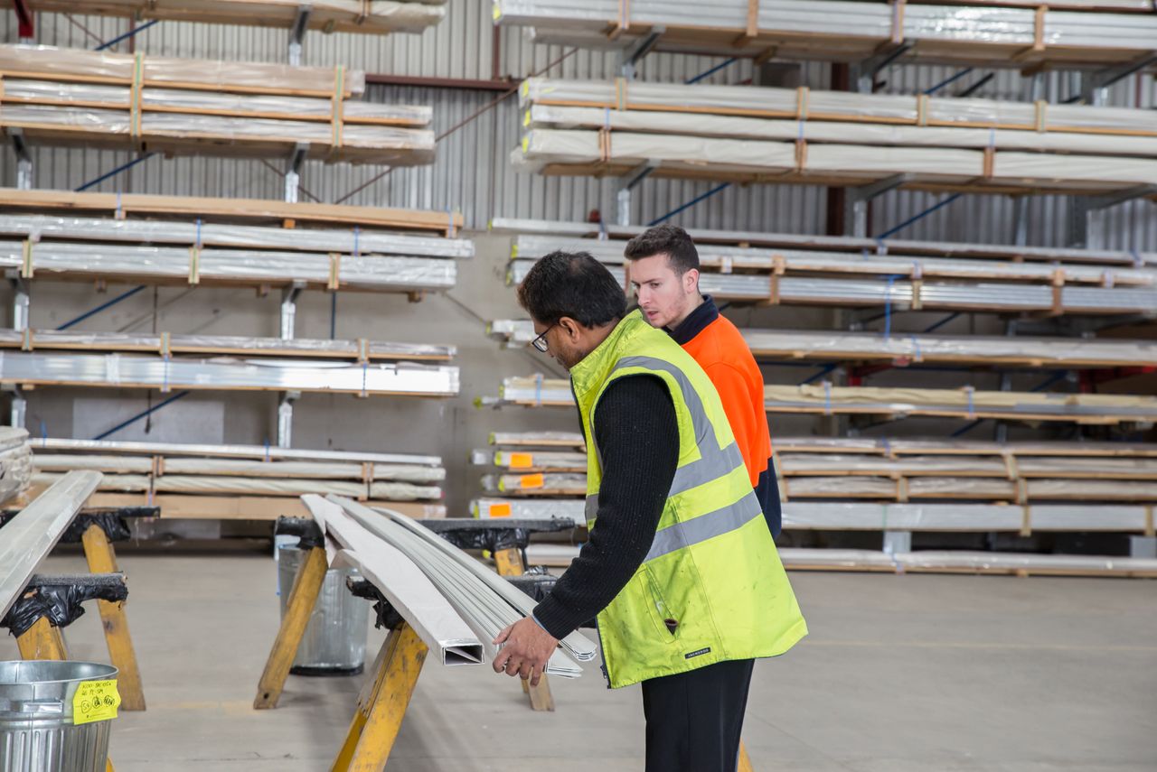 Services Two workers inspecting materials in a warehouse, focusing on quality control and inventory management.