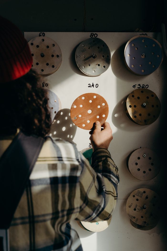 A craftsman choosing a sandpaper disc in a well-lit workshop, emphasizing carpentry tools.